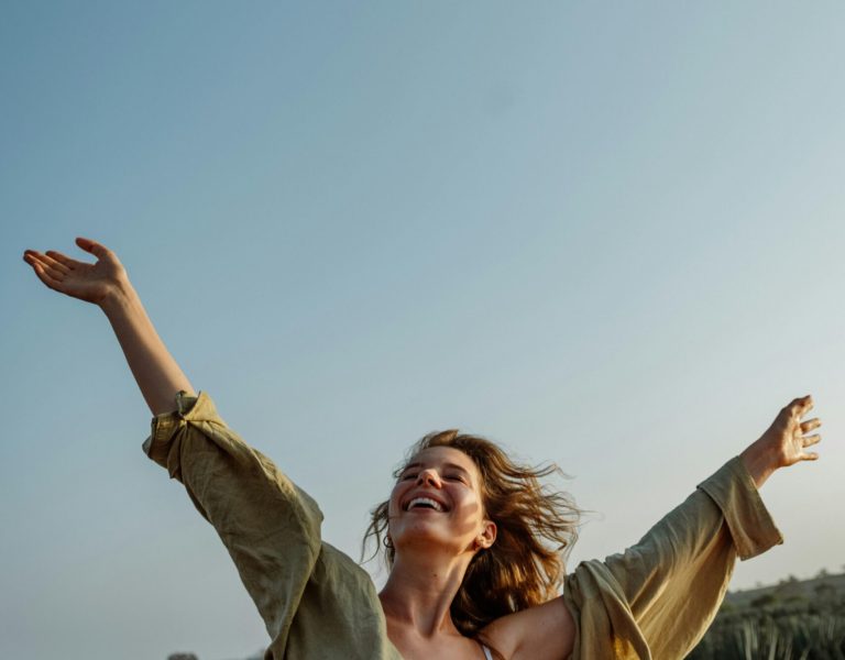 pexels photo 11759953 11759953 Woman joyfully stretches arms beside car on a sunny rural road, embracing freedom.